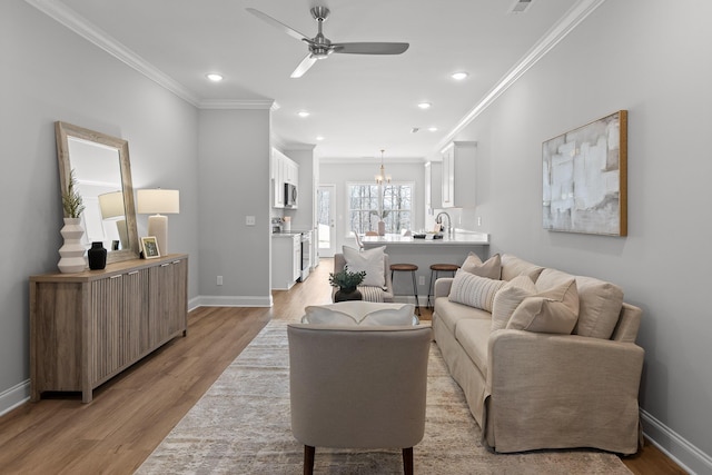 living room with a ceiling fan, baseboards, light wood-style floors, ornamental molding, and recessed lighting