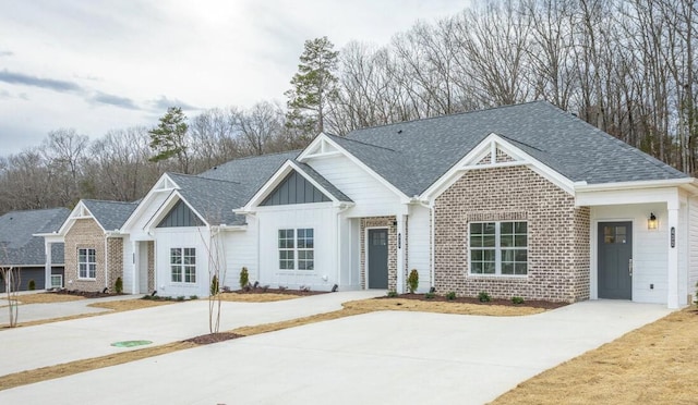 view of front of property with roof with shingles, brick siding, and board and batten siding