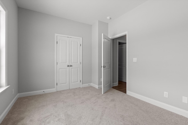 unfurnished bedroom featuring carpet, a closet, and baseboards
