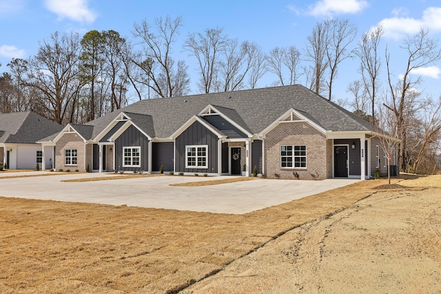 view of front of house featuring board and batten siding, brick siding, and roof with shingles