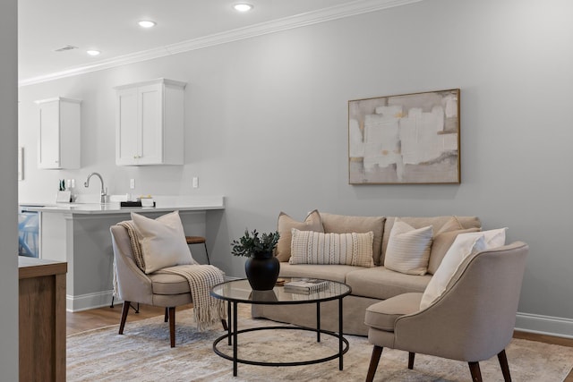 living area featuring light wood finished floors, crown molding, baseboards, and recessed lighting