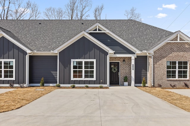 view of front of home with a shingled roof, board and batten siding, and brick siding
