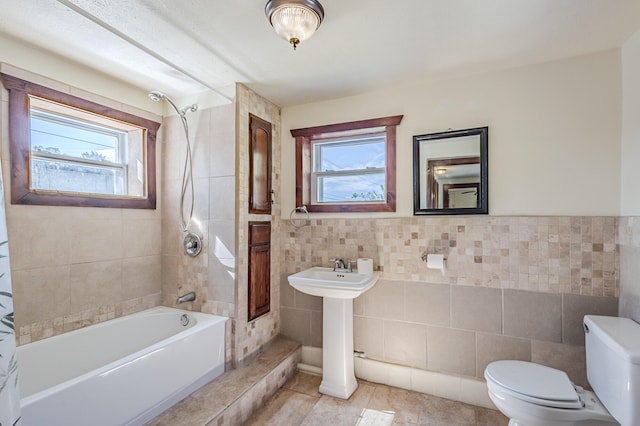 full bathroom with tiled shower / bath combo, tile patterned floors, plenty of natural light, and tile walls