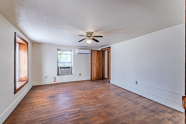 unfurnished bedroom with ceiling fan, dark wood-type flooring, a wall mounted AC, cooling unit, and a textured ceiling