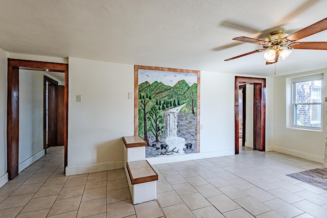 spare room with ceiling fan, light tile patterned floors, and a textured ceiling