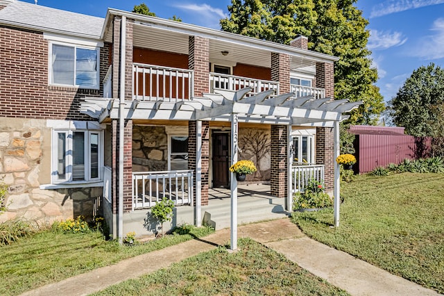 view of front facade with a pergola, a balcony, and a front lawn