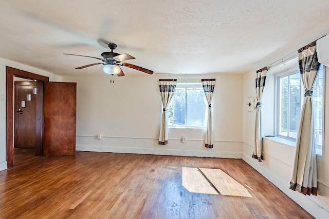 empty room featuring a healthy amount of sunlight, wood-type flooring, and a textured ceiling