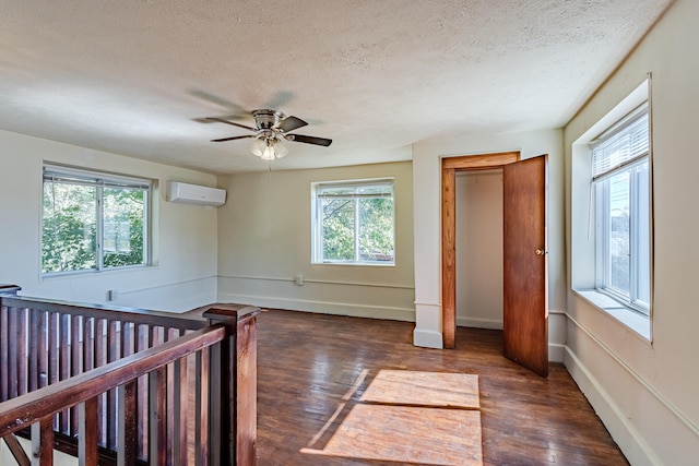 interior space featuring an AC wall unit, ceiling fan, a textured ceiling, and dark hardwood / wood-style floors