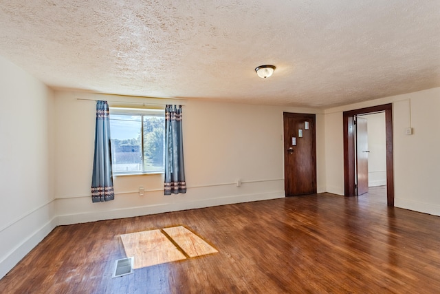 spare room with a textured ceiling and dark wood-type flooring