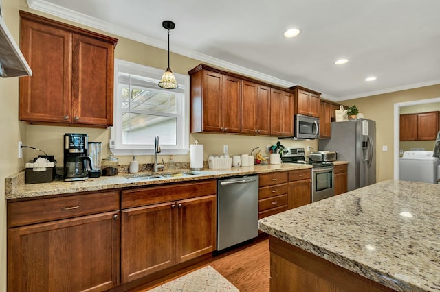 kitchen with washer / dryer, a sink, appliances with stainless steel finishes, and crown molding