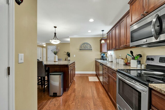 kitchen featuring ornamental molding, wood finished floors, stainless steel appliances, a kitchen island, and a sink
