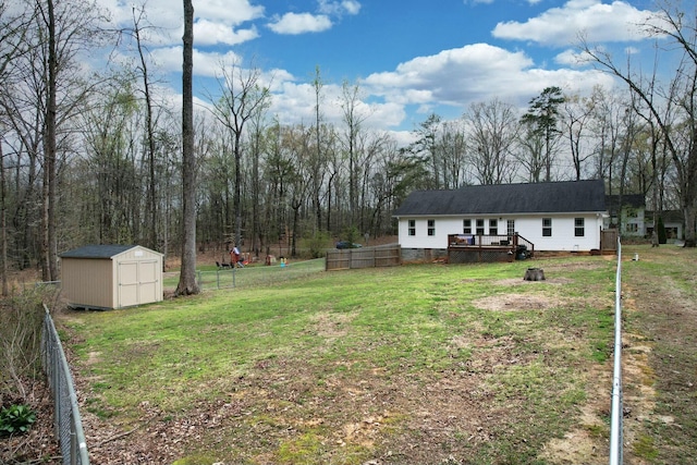 view of yard with an outbuilding, fence, a storage unit, and a deck