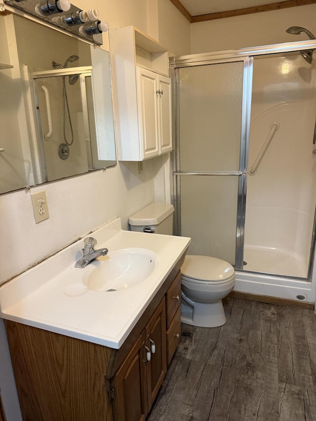 bathroom featuring vanity, toilet, wood finished floors, and a stall shower