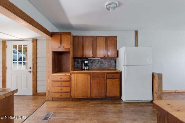 kitchen featuring white refrigerator, tile countertops, hardwood / wood-style floors, and decorative backsplash