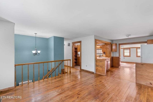 interior space featuring decorative light fixtures, sink, white refrigerator, an inviting chandelier, and light hardwood / wood-style flooring