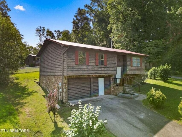 raised ranch featuring a garage and a front lawn