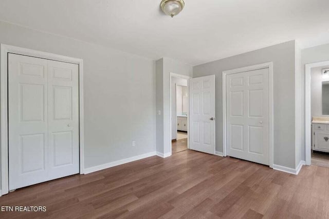 unfurnished bedroom featuring connected bathroom and wood-type flooring