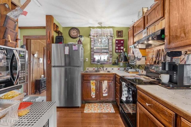 kitchen featuring sink, hardwood / wood-style floors, a notable chandelier, black appliances, and decorative light fixtures