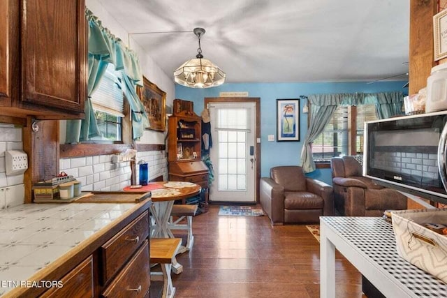 kitchen with tasteful backsplash, decorative light fixtures, tile counters, and plenty of natural light