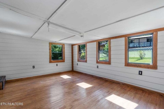 spare room with hardwood / wood-style flooring and wooden walls