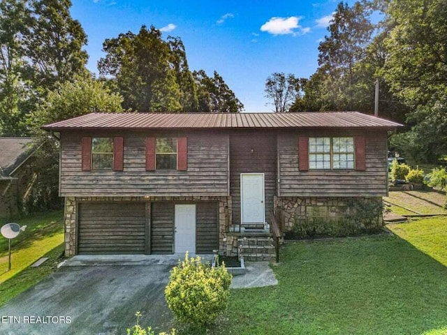 raised ranch featuring a garage and a front lawn