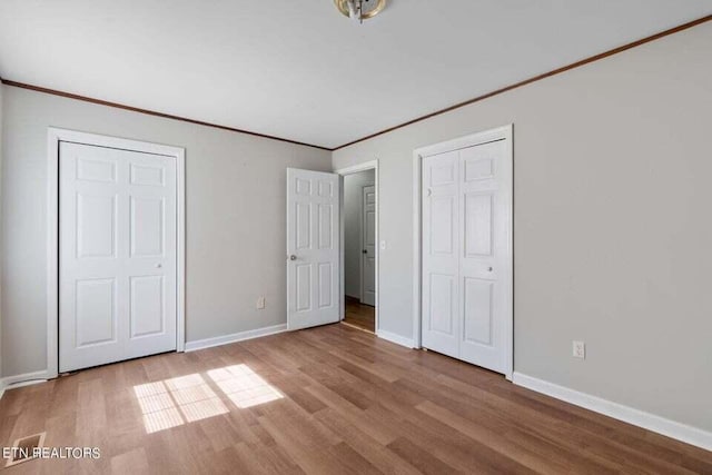 unfurnished bedroom featuring crown molding, light hardwood / wood-style floors, and a closet