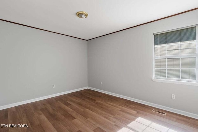 empty room with ornamental molding and wood-type flooring