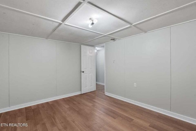 basement featuring a drop ceiling and wood-type flooring