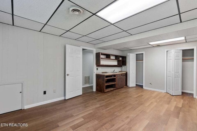 basement featuring a drop ceiling and light wood-type flooring