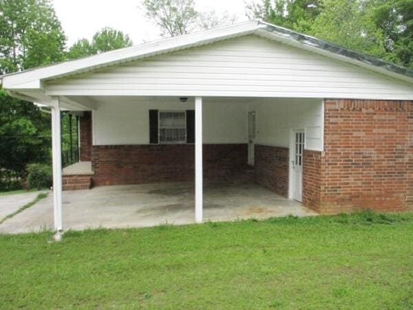 view of home's exterior featuring brick siding, a lawn, and an attached carport