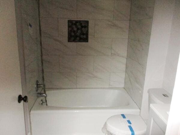 bathroom featuring toilet and washtub / shower combination