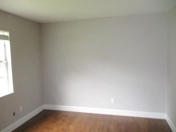 unfurnished room with baseboards and wood finished floors