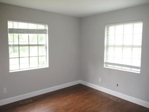 unfurnished room featuring baseboards and dark wood-style flooring