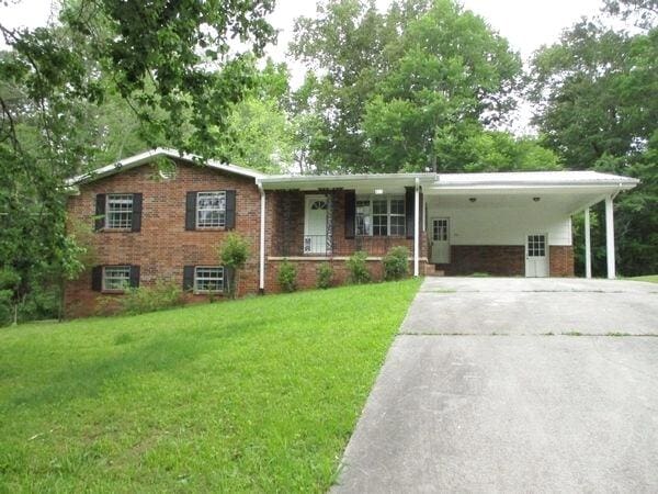 view of front of property with a front lawn, covered porch, concrete driveway, and an attached carport