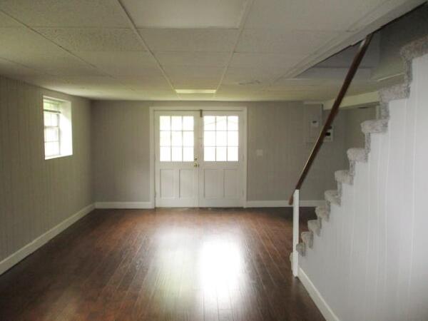 below grade area featuring baseboards, stairway, wood finished floors, and a paneled ceiling