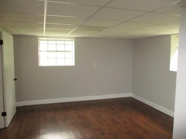 empty room with wood finished floors, baseboards, and a drop ceiling