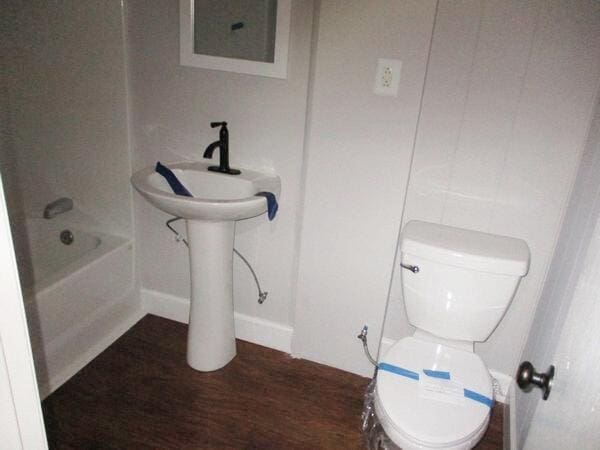 full bathroom featuring toilet, wood finished floors, baseboards, and a sink