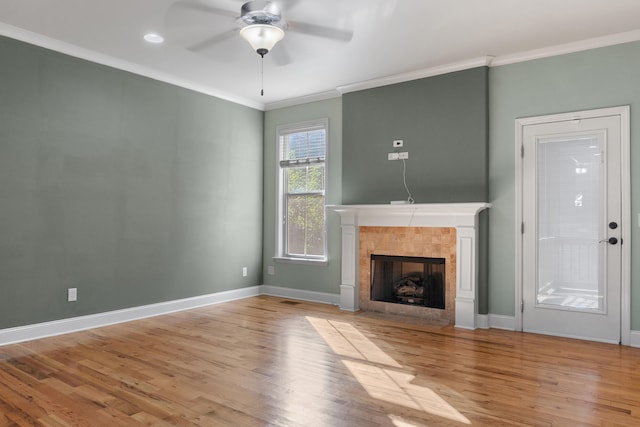 unfurnished living room featuring crown molding, ceiling fan, a tiled fireplace, and light hardwood / wood-style floors