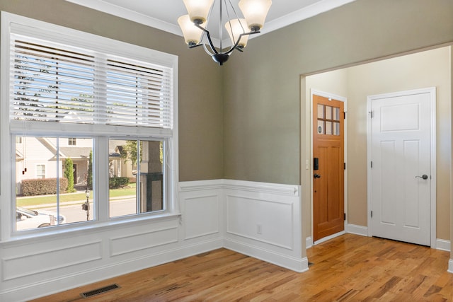 unfurnished dining area featuring crown molding, a chandelier, and light wood-type flooring