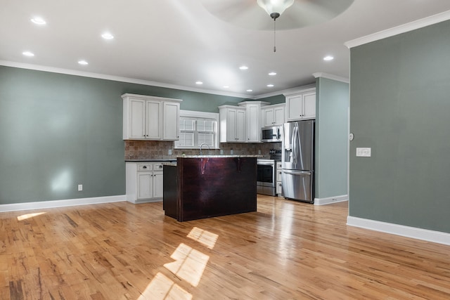 kitchen featuring a kitchen island, white cabinets, decorative backsplash, ornamental molding, and stainless steel appliances