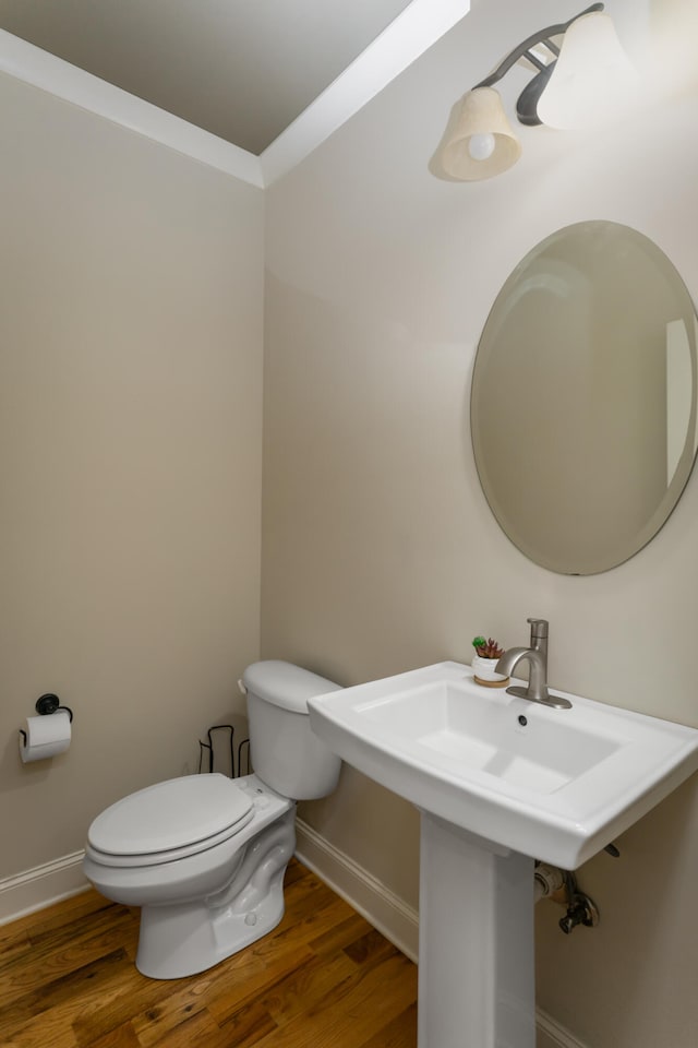 bathroom featuring ornamental molding, toilet, and hardwood / wood-style floors