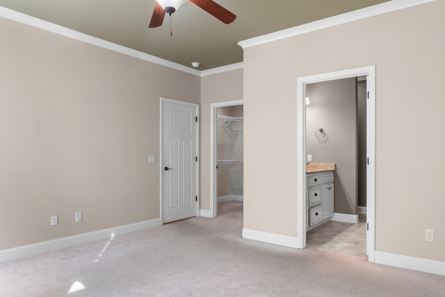 unfurnished bedroom featuring crown molding, a walk in closet, ceiling fan, and light carpet