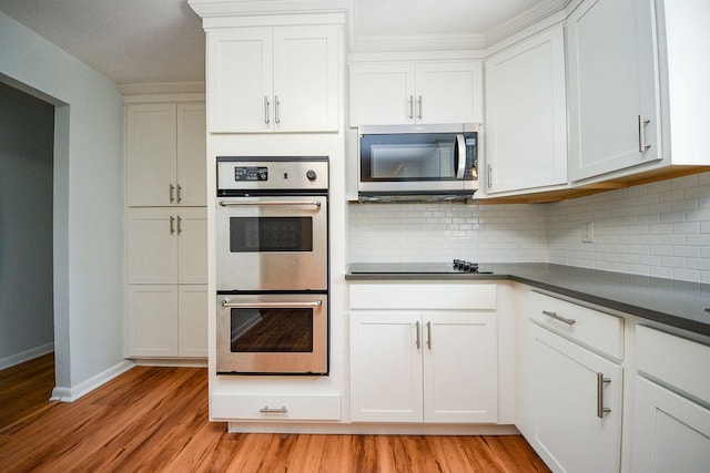 kitchen featuring decorative backsplash, appliances with stainless steel finishes, light wood-type flooring, and white cabinetry