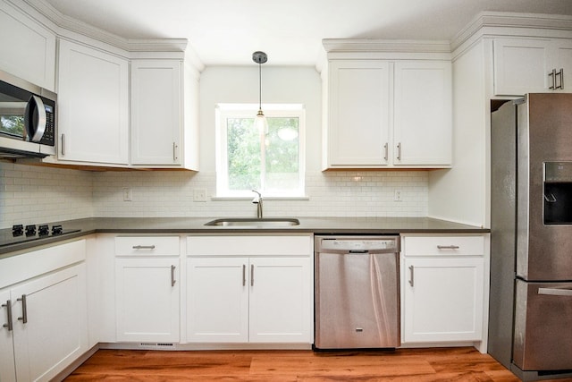 kitchen featuring hanging light fixtures, sink, appliances with stainless steel finishes, light hardwood / wood-style floors, and white cabinetry