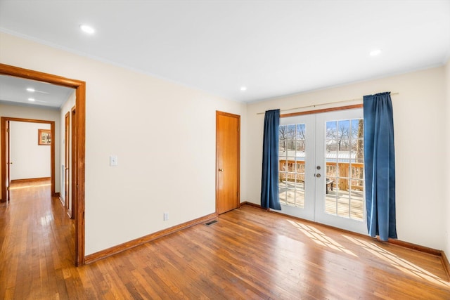 empty room featuring hardwood / wood-style flooring, crown molding, and french doors