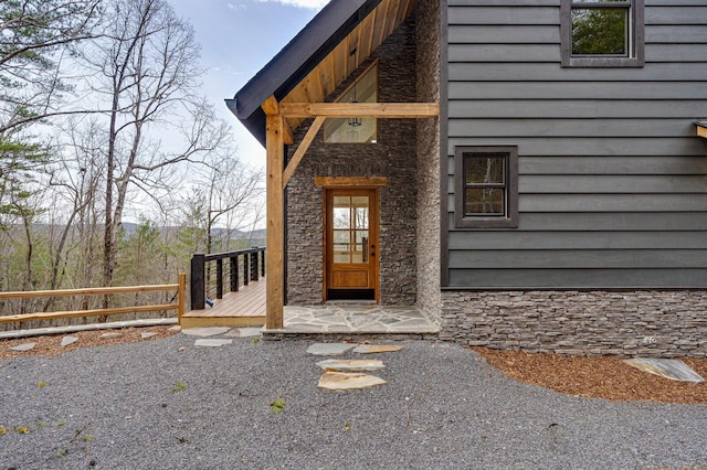 entrance to property with stone siding and a wooden deck