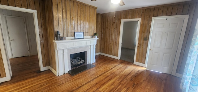 unfurnished living room with wood walls, light wood-style flooring, and ceiling fan