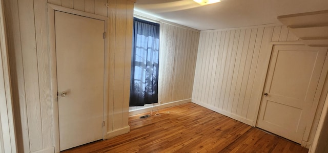 unfurnished room featuring wood finished floors and wood walls