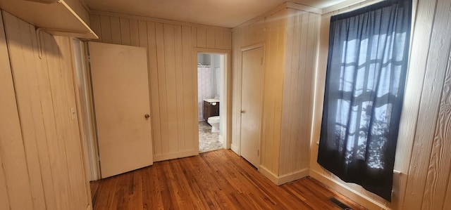 hall with wood finished floors, visible vents, and wood walls