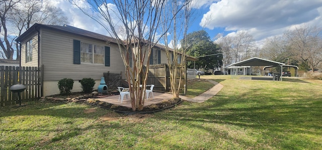 view of property exterior with a carport, a patio area, a yard, and fence